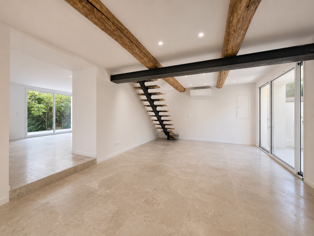 Pièce de vie rénovée à Puyricard avec espace ouvert, escalier contemporain suspendu, poutres apparentes et larges baies vitrées donnant sur le jardin.