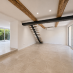 Pièce de vie rénovée à Puyricard avec espace ouvert, escalier contemporain suspendu, poutres apparentes et larges baies vitrées donnant sur le jardin.