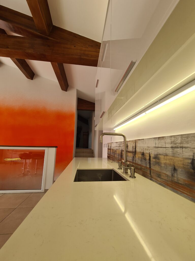 Cuisine sur mesure avec plan de travail en quartz, évier sous plan, robinetterie design et éclairage LED après la transformation d'une ancienne piscine intérieure en loft à Châteauneuf-les-Martigues.
